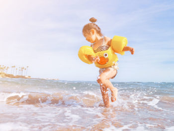 young-girl-splashing-in-ocean-wearing-float